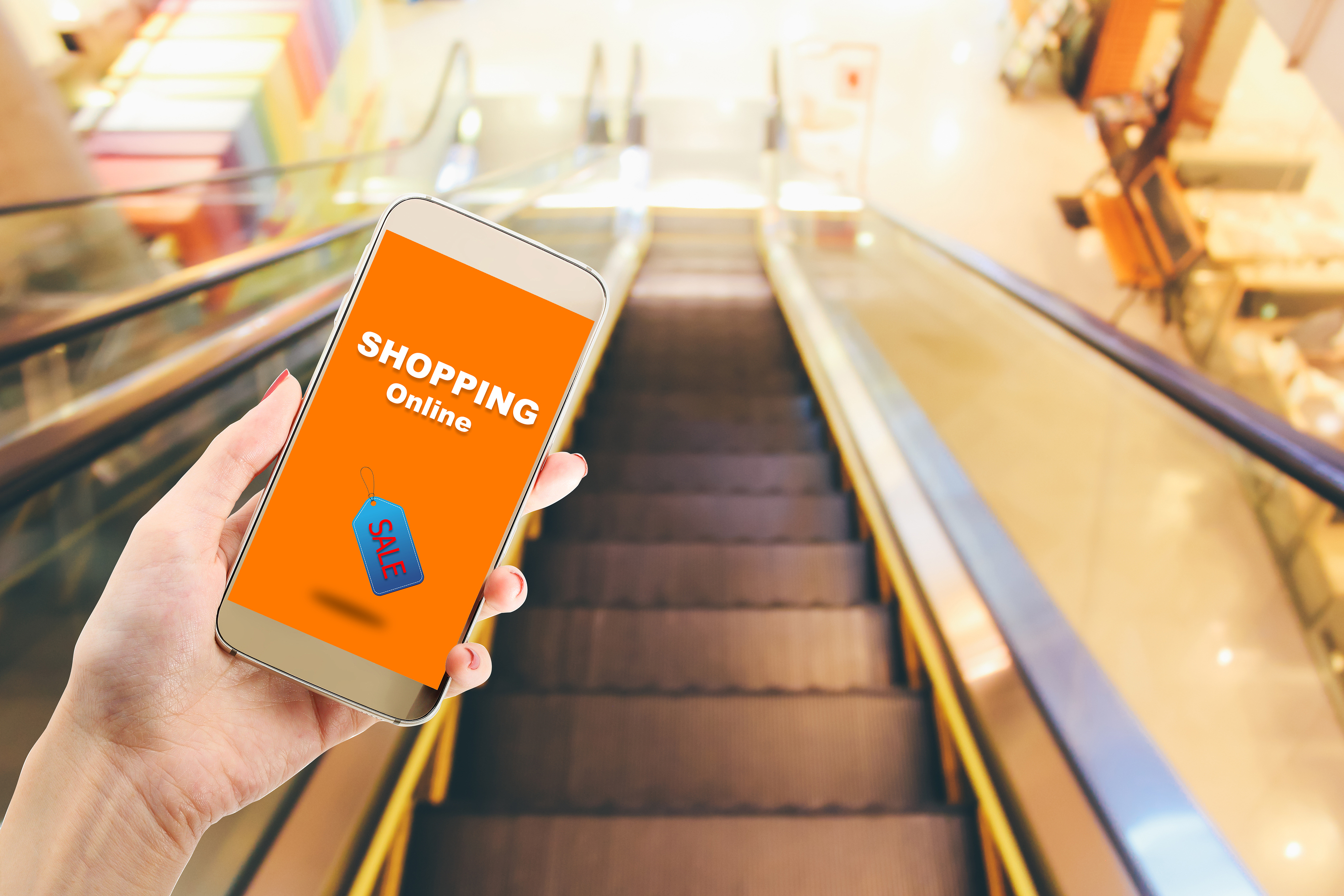 shopping online via application on smartphone - woman hand hold smartphone on blur escalator in department store background