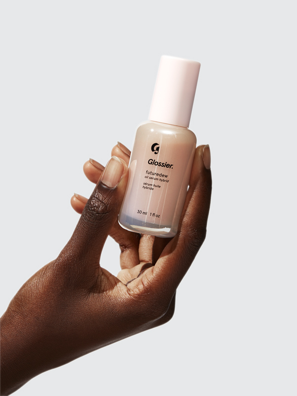 Woman holding a Glossier futuredew bottle in her hand