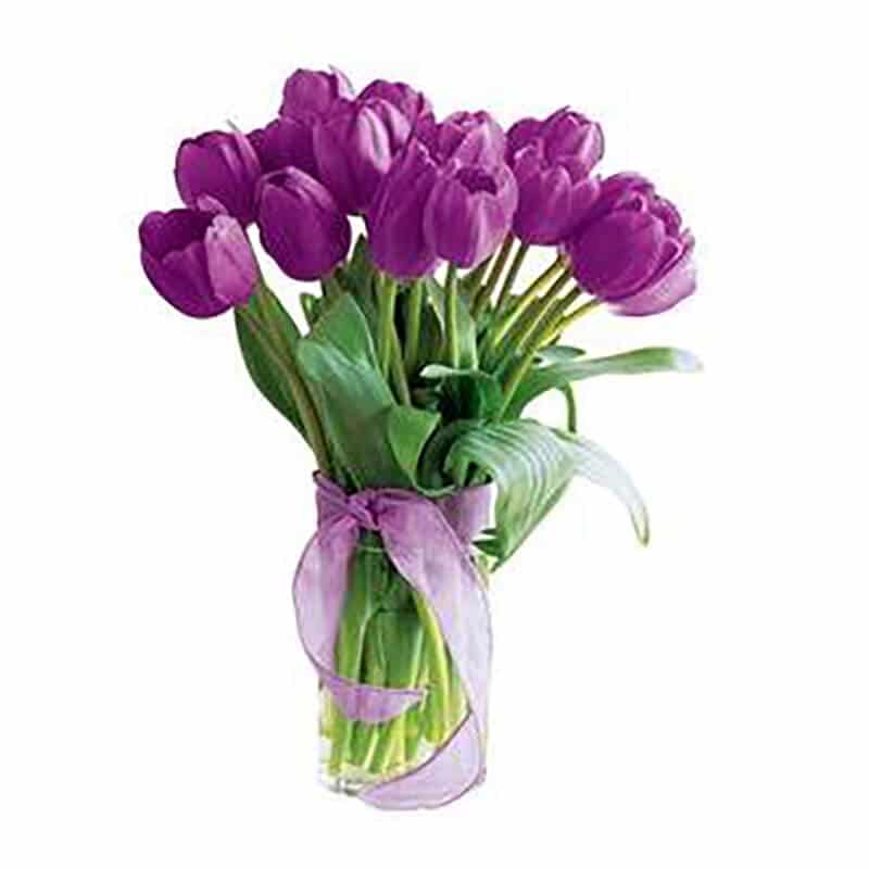 twenty purple tulips in a glass vase